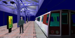 A man stands on a train platform at night next to a stopped train, with numbers marked on the ground and a digital billboard in the background.